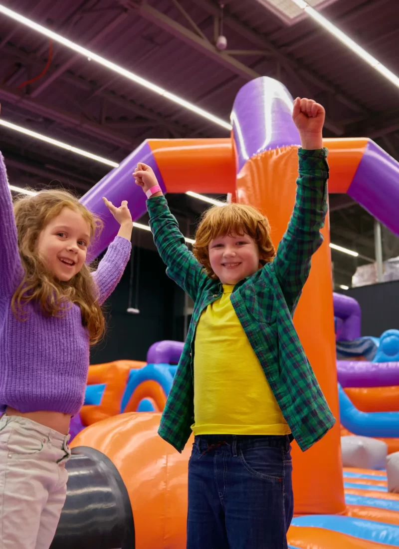 portrait-of-happy-children-with-raised-hands-up Two kids raising hands in the inflatable bouncing house.
